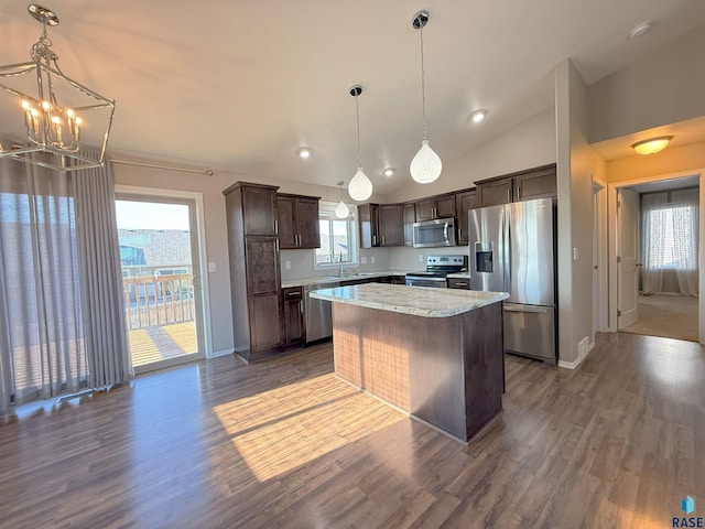 kitchen with stainless steel appliances, a center island, dark brown cabinets, hanging light fixtures, and dark wood-type flooring