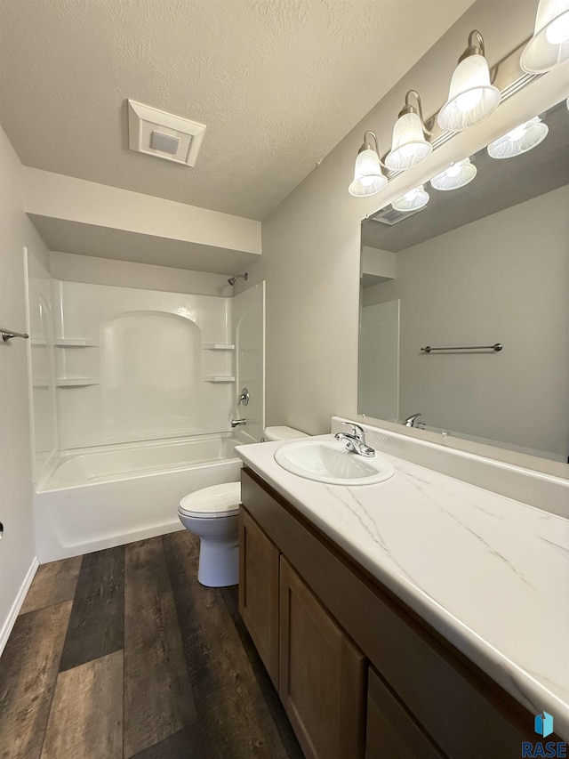 full bathroom featuring hardwood / wood-style floors, toilet, vanity, a textured ceiling, and shower / bathing tub combination