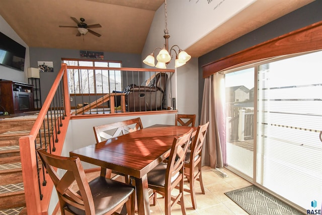 tiled dining area with ceiling fan with notable chandelier and lofted ceiling