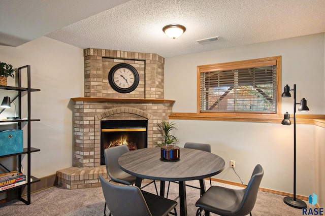 dining room with carpet, a textured ceiling, and a brick fireplace