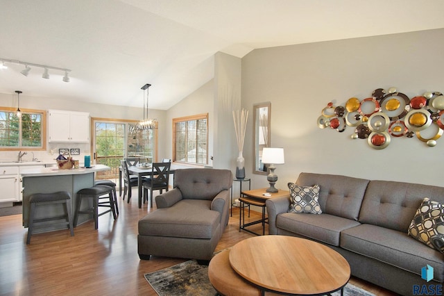 living room featuring sink, dark hardwood / wood-style flooring, vaulted ceiling, and an inviting chandelier