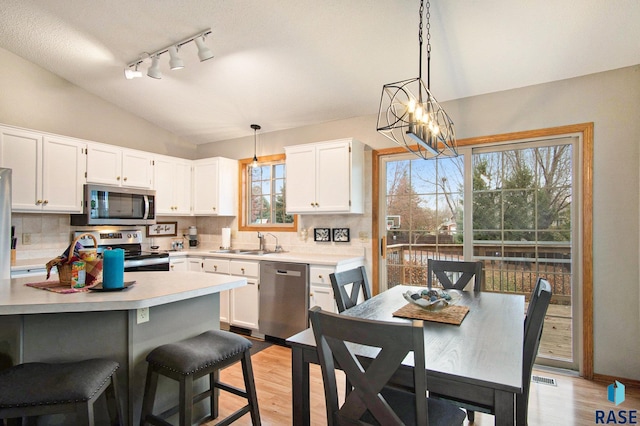 kitchen featuring light wood-type flooring, backsplash, stainless steel appliances, sink, and white cabinets