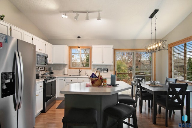 kitchen with white cabinetry, hanging light fixtures, and appliances with stainless steel finishes