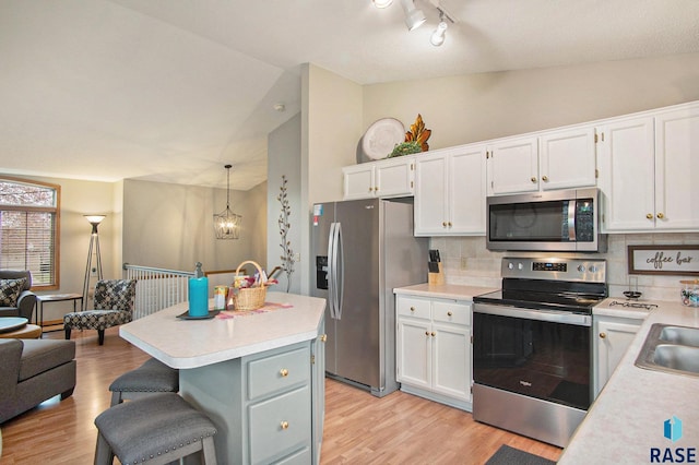 kitchen with tasteful backsplash, white cabinetry, stainless steel appliances, and decorative light fixtures