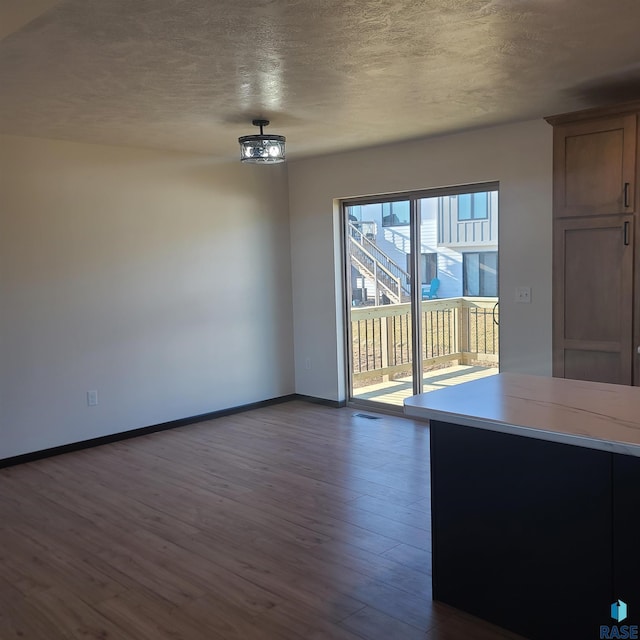 unfurnished dining area featuring a chandelier, a textured ceiling, and dark wood-type flooring