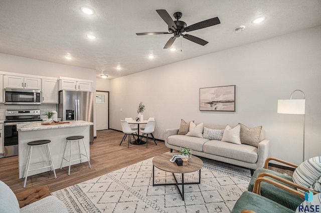 living room featuring light wood-type flooring and ceiling fan