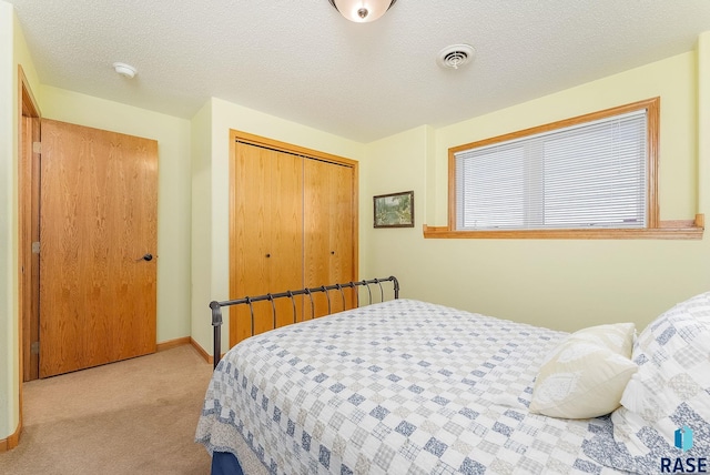 bedroom featuring a textured ceiling, light carpet, and a closet