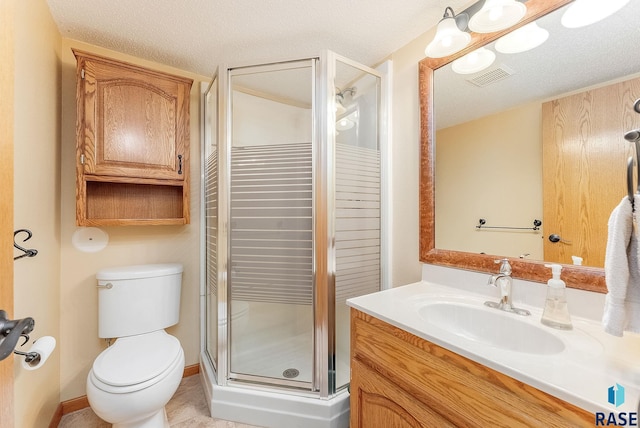 bathroom with vanity, tile patterned floors, toilet, a textured ceiling, and a shower with shower door