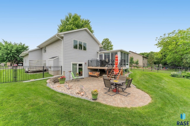 back of property featuring a lawn, a patio area, a sunroom, and a wooden deck