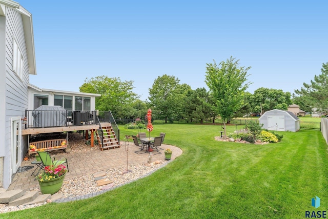 view of yard with a storage shed, a patio area, and a wooden deck