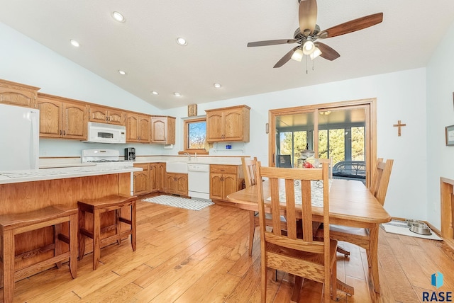 kitchen with light wood-type flooring, white appliances, ceiling fan, a breakfast bar area, and lofted ceiling