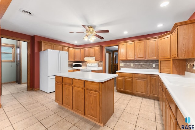 kitchen featuring decorative backsplash, white appliances, ceiling fan, a center island, and light tile patterned flooring