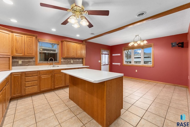 kitchen with ceiling fan with notable chandelier, backsplash, a center island, and sink