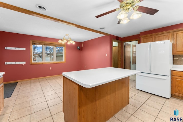 kitchen with ceiling fan with notable chandelier, light tile patterned floors, pendant lighting, white fridge, and a kitchen island