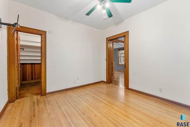 unfurnished bedroom with a closet, light hardwood / wood-style floors, a spacious closet, and ceiling fan