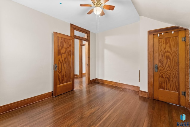 empty room with ceiling fan, dark hardwood / wood-style flooring, and vaulted ceiling