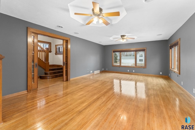 unfurnished living room featuring a tray ceiling, ceiling fan, and light hardwood / wood-style floors