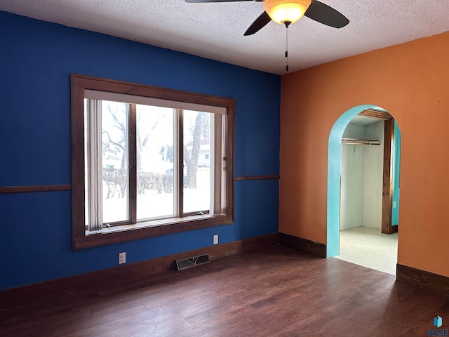 spare room featuring a textured ceiling, ceiling fan, and dark wood-type flooring