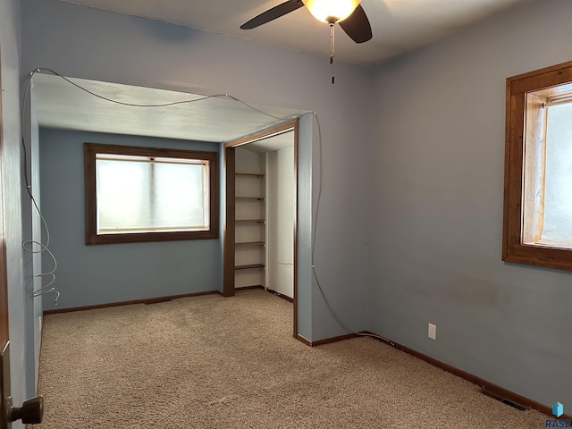 unfurnished bedroom with multiple windows, ceiling fan, and light colored carpet