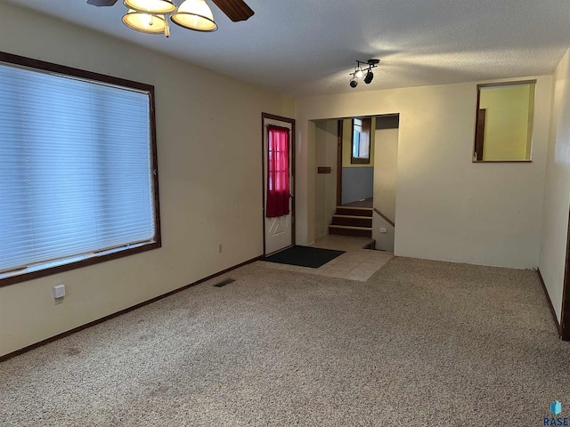 carpeted foyer featuring ceiling fan and a textured ceiling