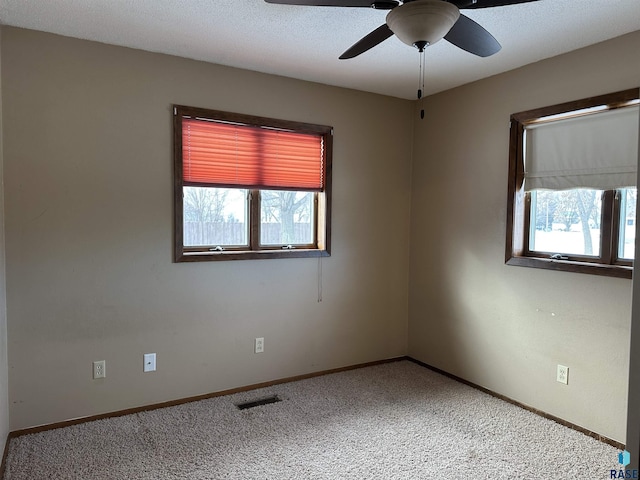 empty room featuring carpet, a wealth of natural light, and ceiling fan