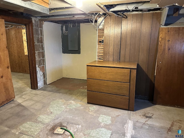 basement featuring electric panel and wooden walls