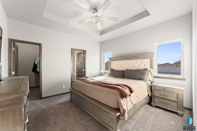 bedroom featuring ceiling fan, dark carpet, and a raised ceiling