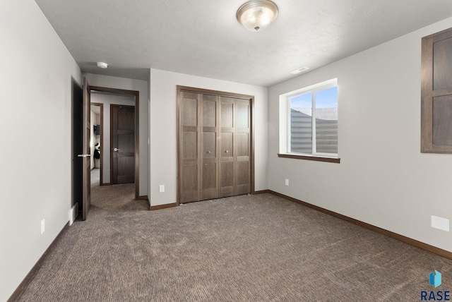 unfurnished bedroom featuring dark carpet and a closet