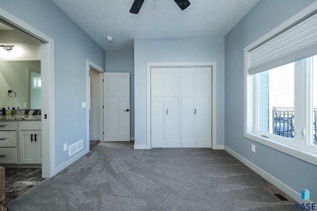 unfurnished bedroom featuring carpet flooring, ceiling fan, a textured ceiling, and a closet