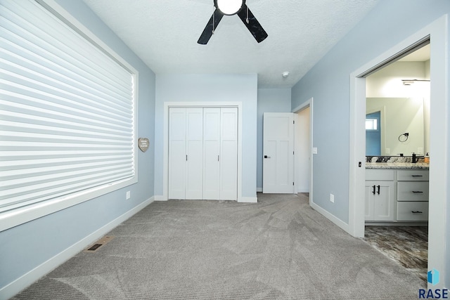 unfurnished bedroom featuring a textured ceiling, ceiling fan, light carpet, and ensuite bath