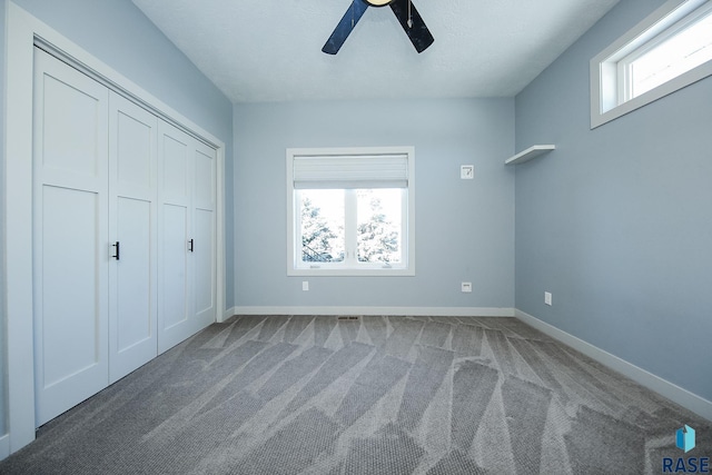 unfurnished bedroom with ceiling fan, a closet, carpet floors, and multiple windows