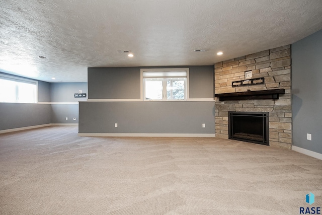 unfurnished living room with a fireplace, a textured ceiling, light colored carpet, and a healthy amount of sunlight