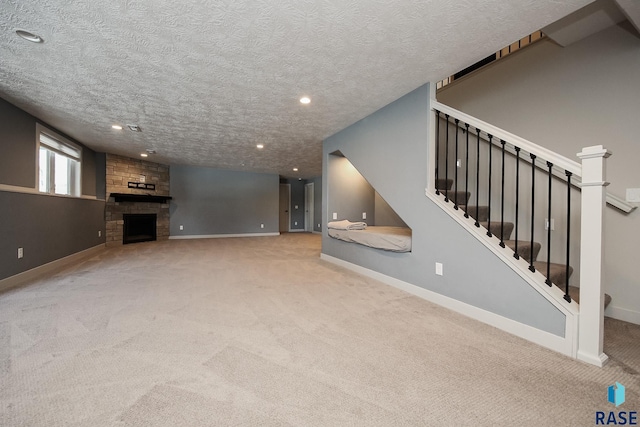 unfurnished living room with a textured ceiling, a stone fireplace, and light carpet