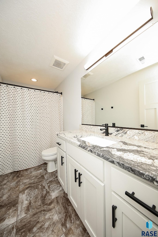 bathroom featuring curtained shower, vanity, and toilet