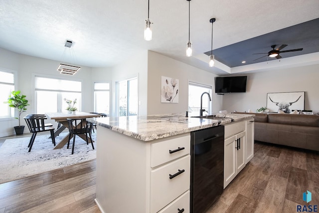 kitchen featuring dark hardwood / wood-style flooring, sink, decorative light fixtures, white cabinetry, and an island with sink