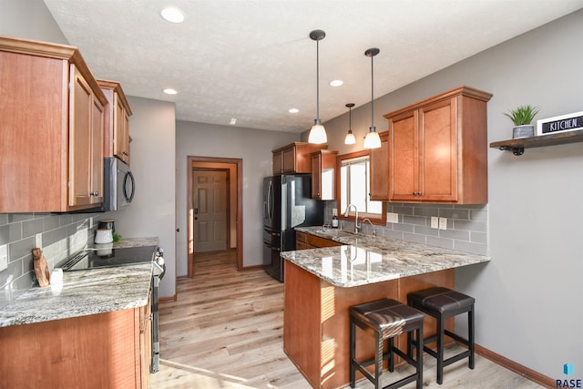 kitchen with decorative light fixtures, a kitchen breakfast bar, appliances with stainless steel finishes, and tasteful backsplash