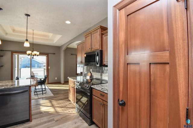 kitchen featuring stainless steel dishwasher, range with electric stovetop, light hardwood / wood-style floors, a tray ceiling, and decorative backsplash