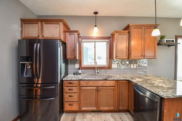 kitchen featuring light stone counters, stainless steel appliances, and hanging light fixtures