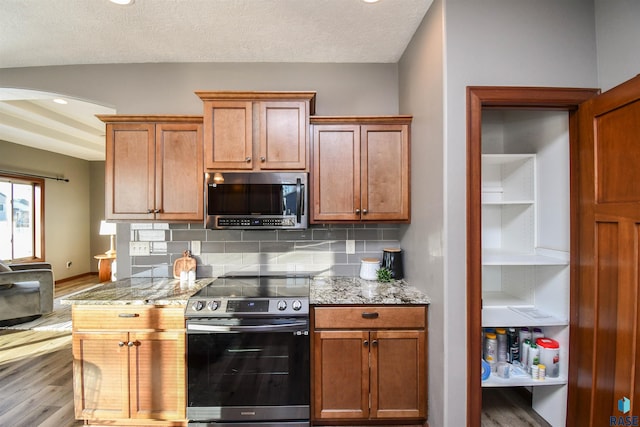 kitchen featuring decorative backsplash, appliances with stainless steel finishes, light wood-type flooring, and light stone countertops