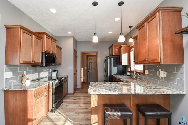 kitchen featuring pendant lighting, sink, light hardwood / wood-style flooring, appliances with stainless steel finishes, and tasteful backsplash