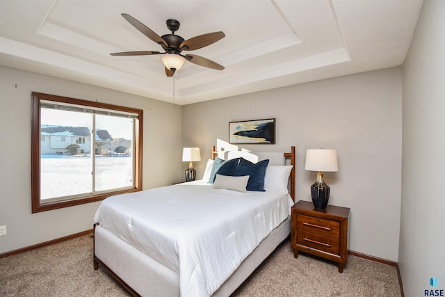 bedroom with light carpet, a tray ceiling, and ceiling fan