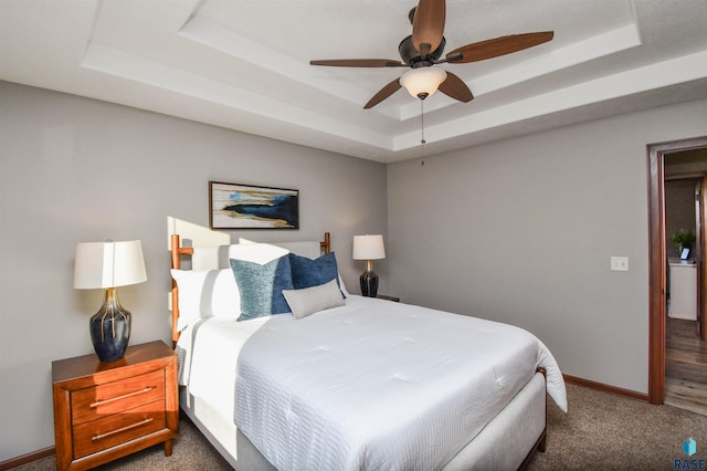 carpeted bedroom with ceiling fan and a tray ceiling