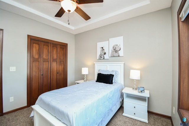 bedroom featuring carpet flooring, a raised ceiling, ceiling fan, and a closet