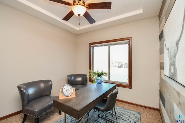 office space with a raised ceiling, ceiling fan, and carpet floors