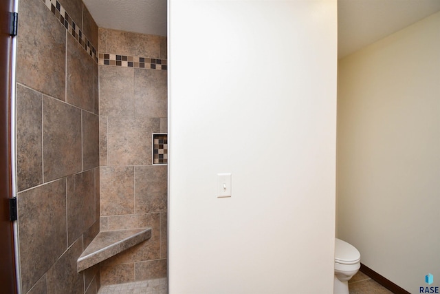 bathroom with tile patterned floors, a tile shower, and toilet