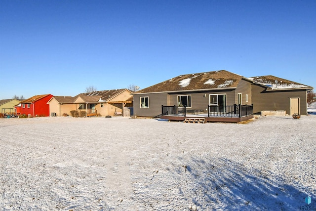 snow covered back of property featuring a wooden deck