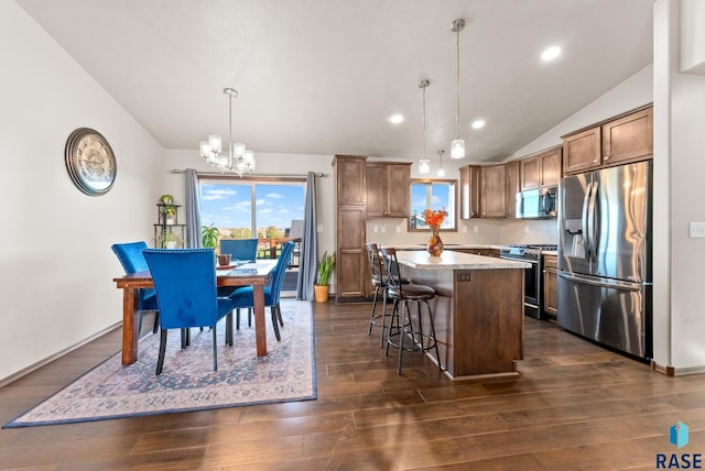 kitchen featuring a center island, a kitchen breakfast bar, dark hardwood / wood-style floors, pendant lighting, and appliances with stainless steel finishes