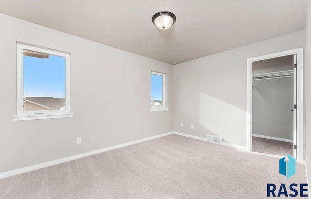 unfurnished bedroom featuring multiple windows, light carpet, and a closet