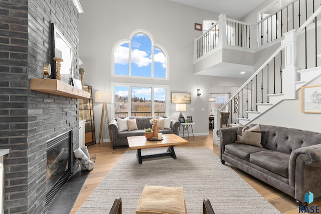 living room featuring a high ceiling, a brick fireplace, and hardwood / wood-style flooring