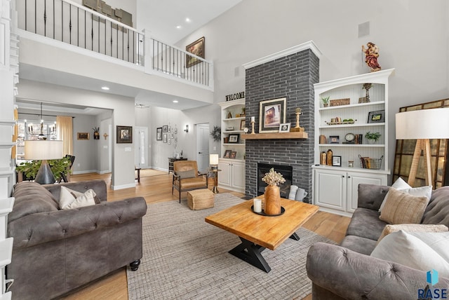 living room featuring a high ceiling, light hardwood / wood-style floors, and a brick fireplace